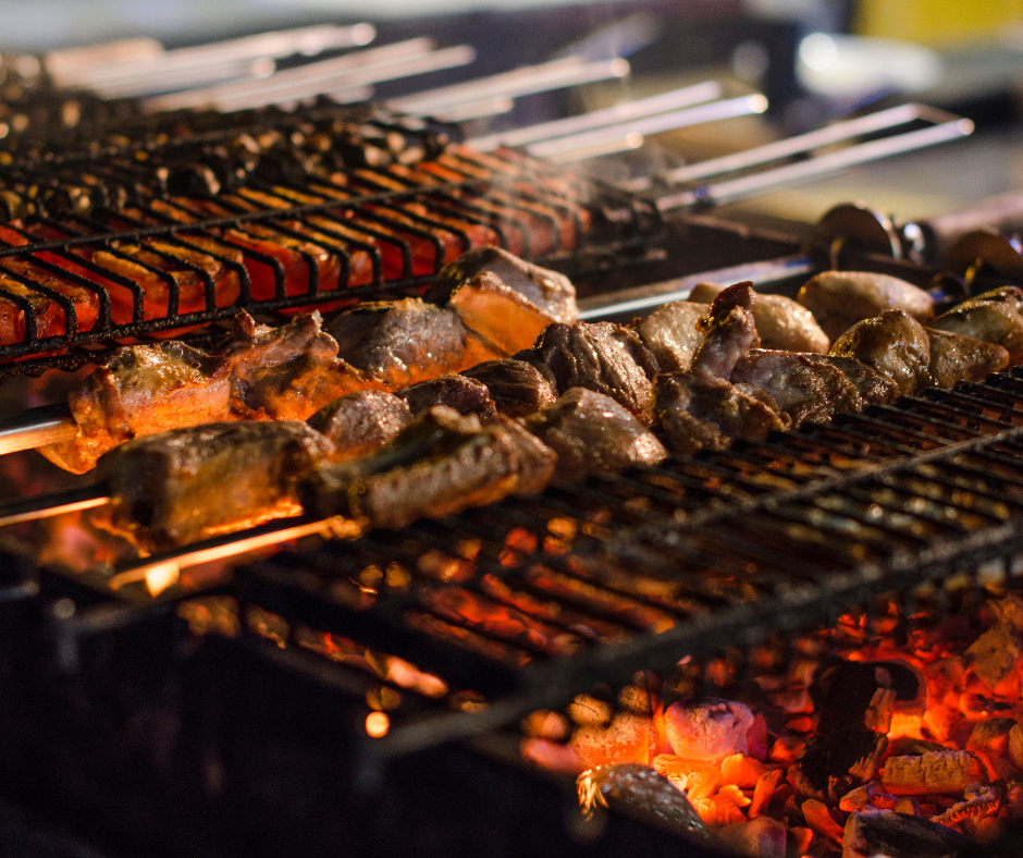 Meat skewers cooking over an open charcoal grill